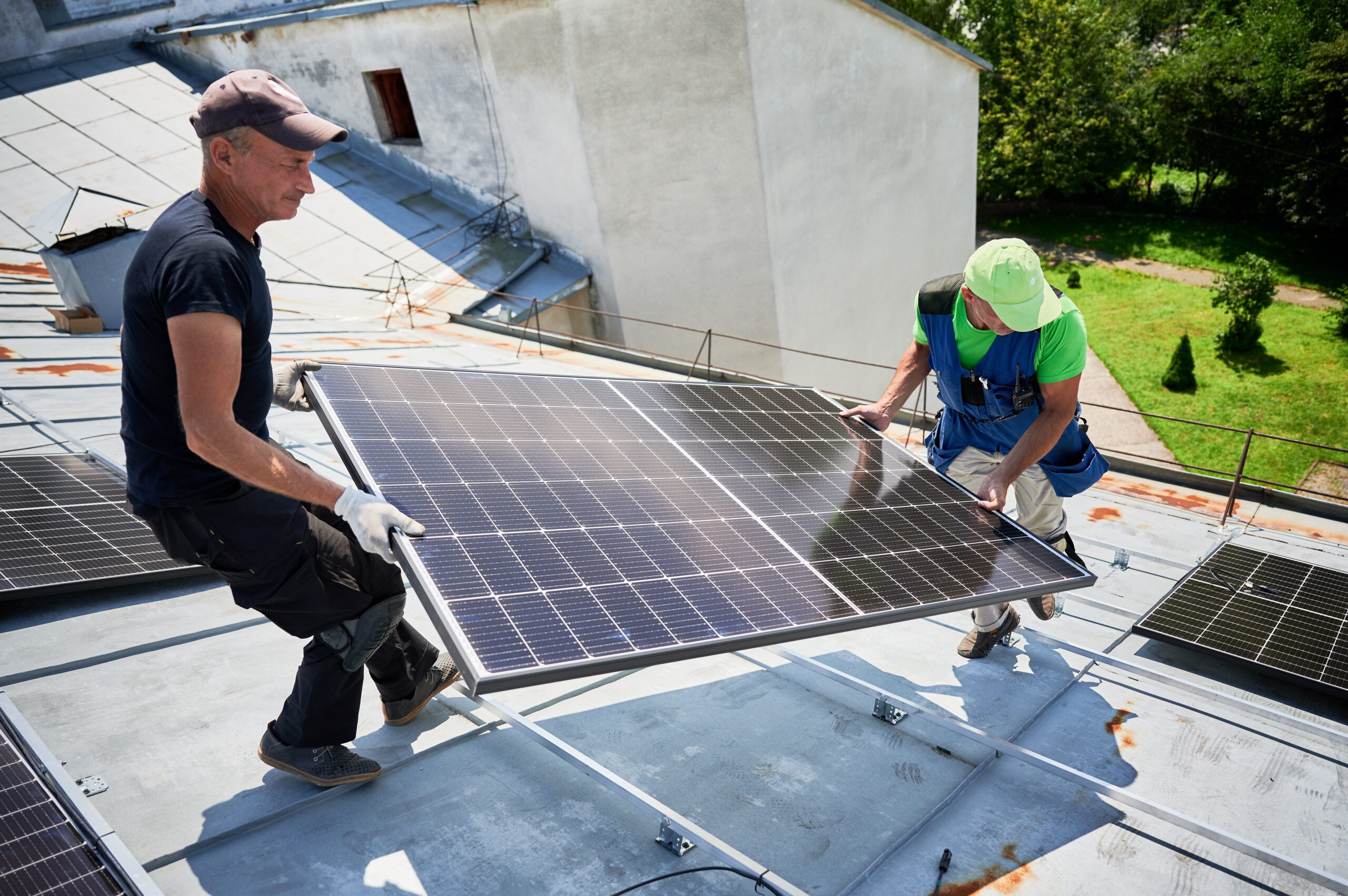 Workers building solar panel system on roof of house. Installers carrying photovoltaic solar module